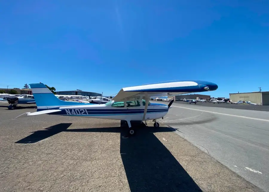 Single-engine airplane parked on the tarmac under a blue sky