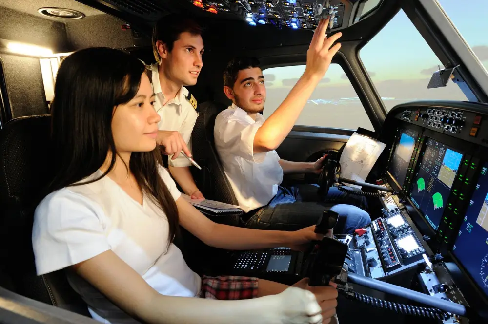 Flight instructor pointing out controls to students in an aircraft simulator.