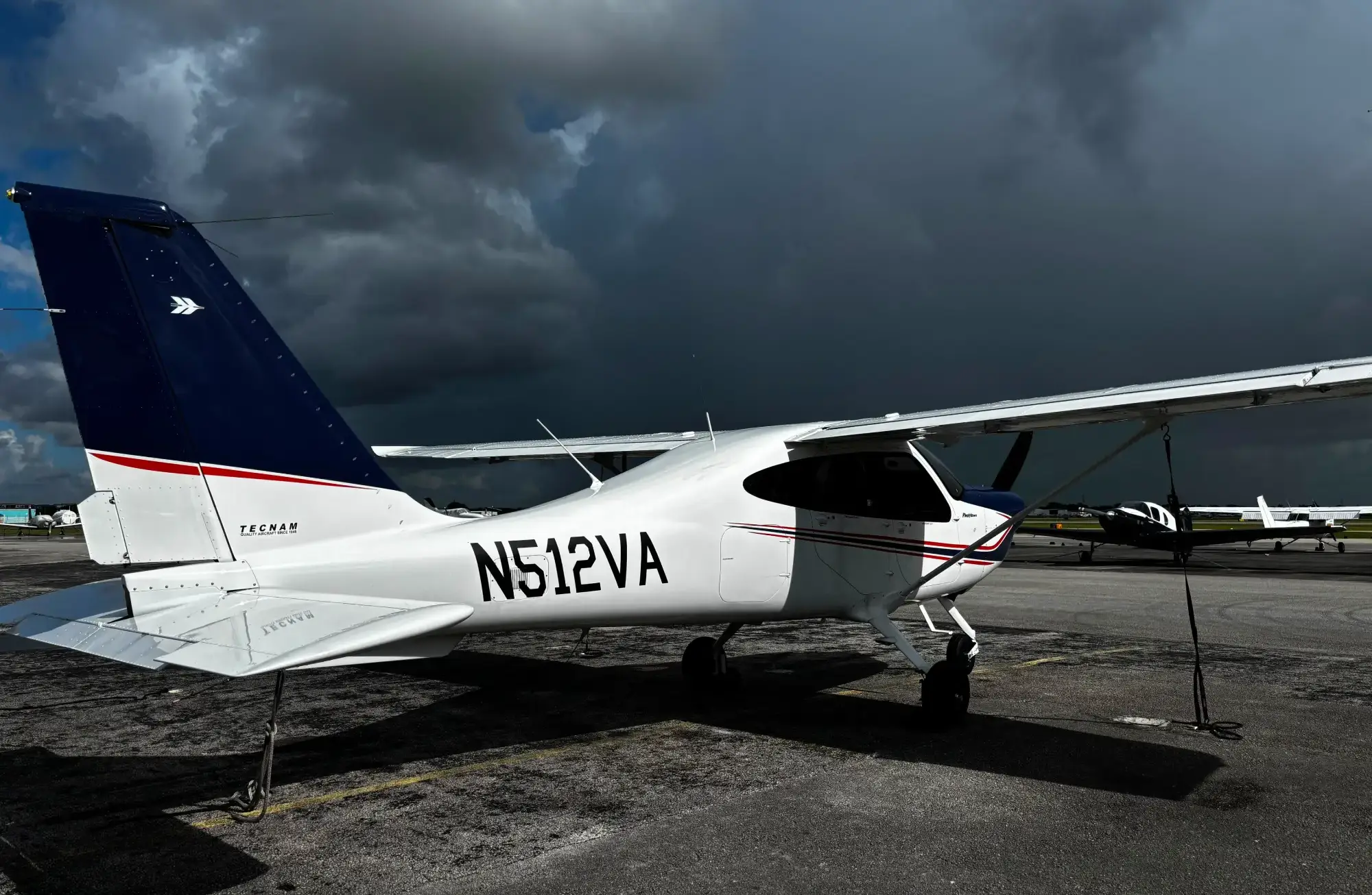 Rear three-quarter view of a single-engine airplane under a stormy sky