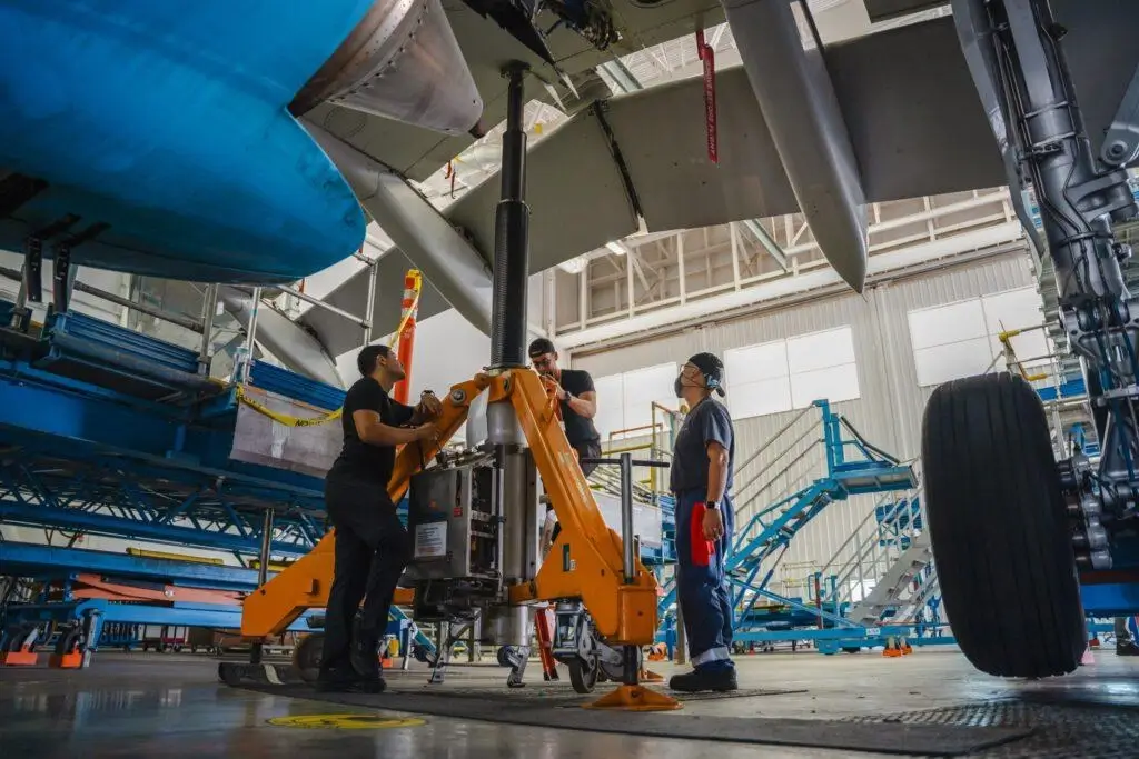 "Mechanics using hydraulic equipment in an aircraft hangar.